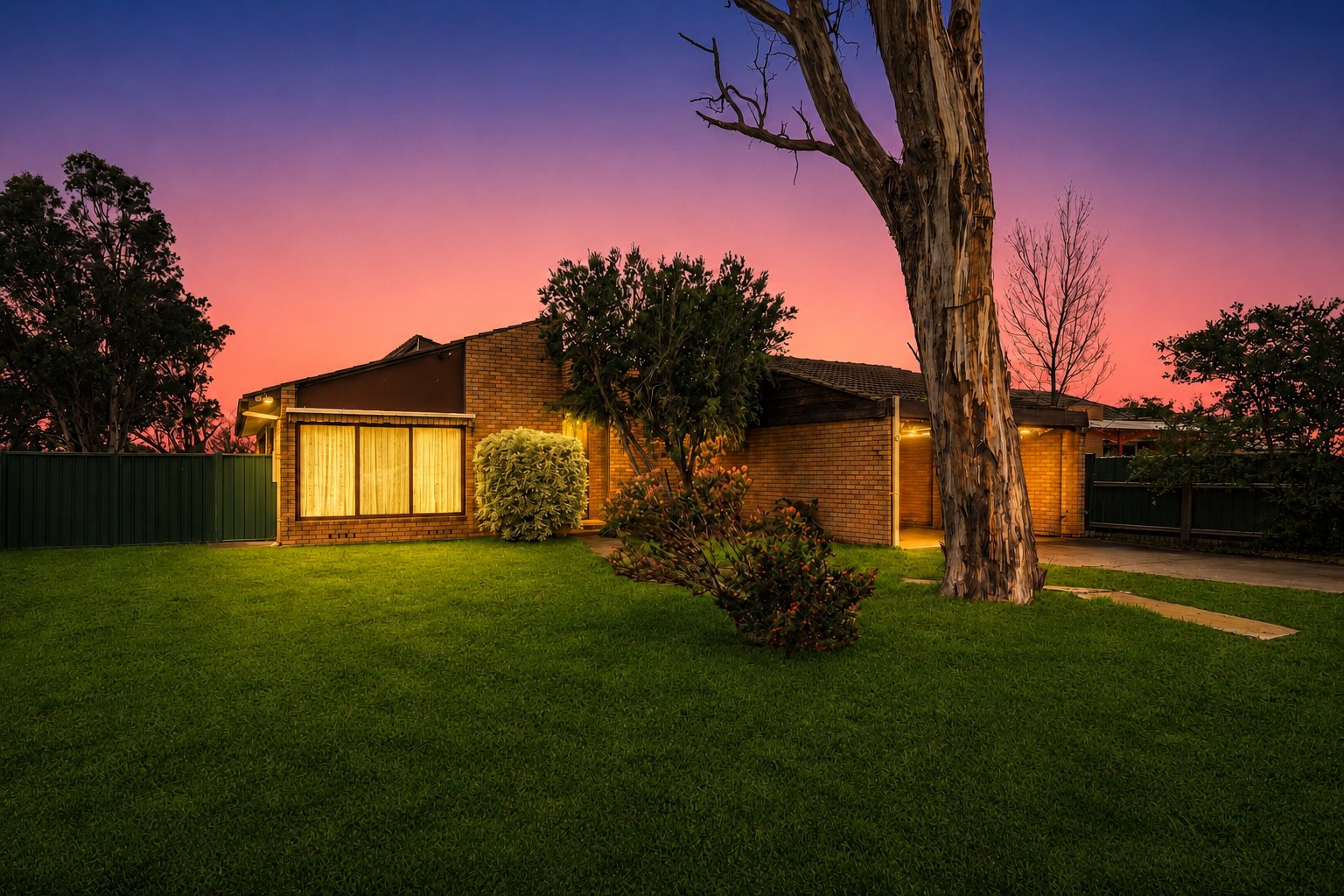 A Goulburn home glowing at dusk beneath its old gum tree